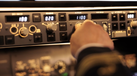 Captain pushing buttons to fix altitude level on control panel command, using navigation switch to fly airplane jet. Power radar with dashboard and handle to takeoff with plane. Close up.